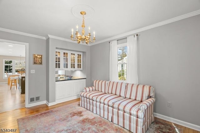 sitting room featuring a notable chandelier, light wood-type flooring, visible vents, and a healthy amount of sunlight