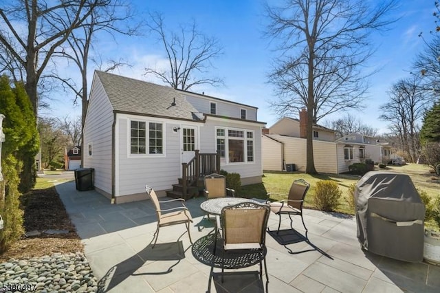 rear view of property featuring a fire pit, a shingled roof, and a patio area