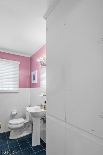 bathroom featuring toilet, a wainscoted wall, tile walls, tile patterned floors, and crown molding