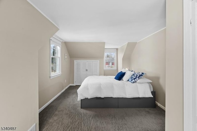 bedroom with lofted ceiling, baseboards, and dark colored carpet