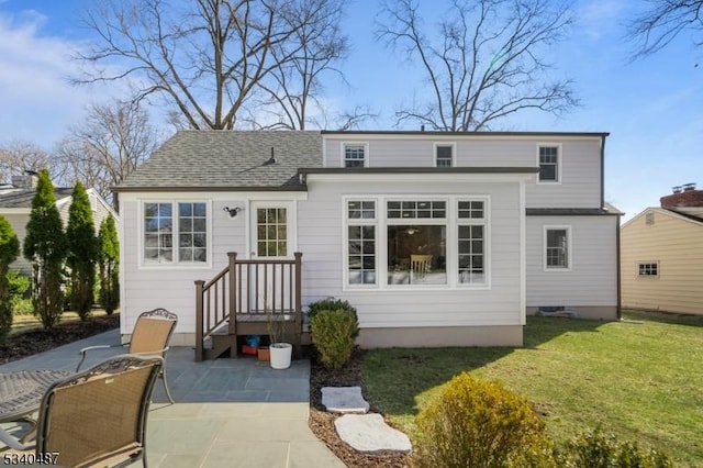 rear view of house featuring a shingled roof and a lawn