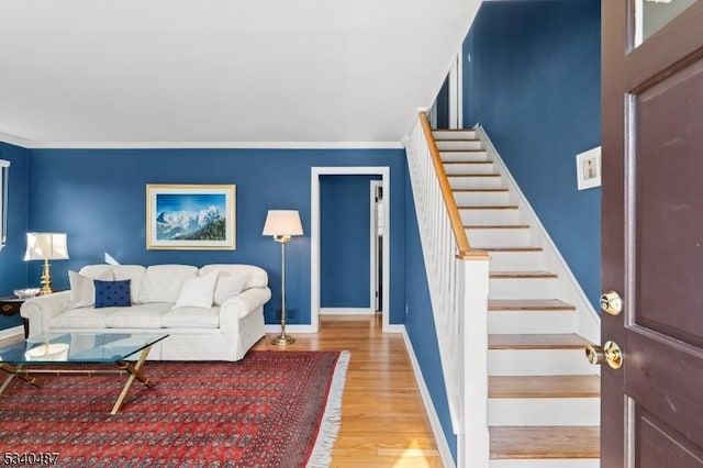 living room featuring crown molding, stairway, baseboards, and wood finished floors