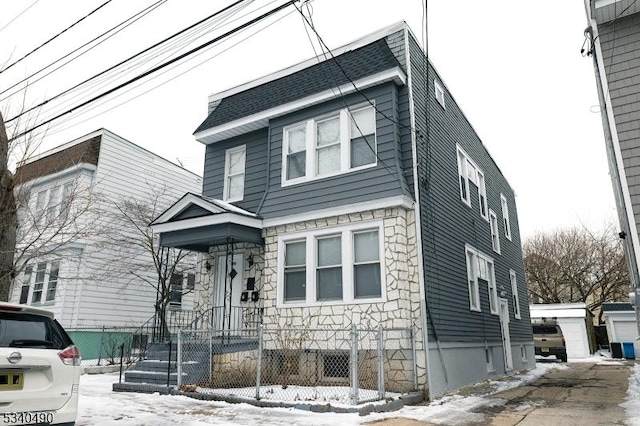 view of front of home featuring stone siding and roof with shingles