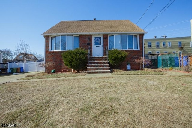 view of front facade featuring entry steps, brick siding, and fence