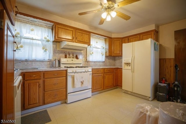 kitchen featuring brown cabinetry, white appliances, light countertops, and under cabinet range hood