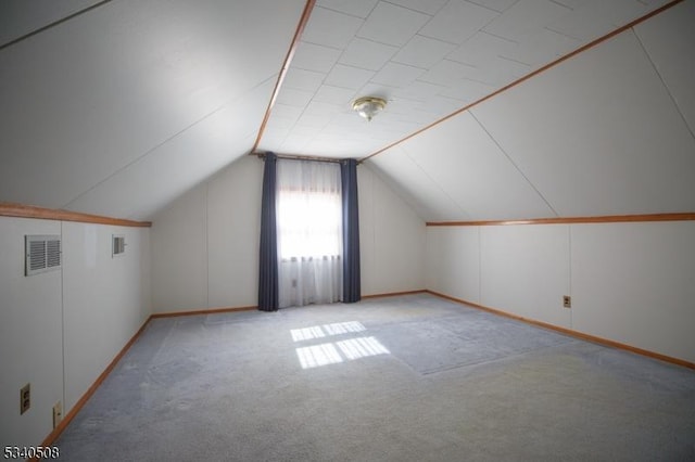 additional living space featuring vaulted ceiling, visible vents, and light colored carpet