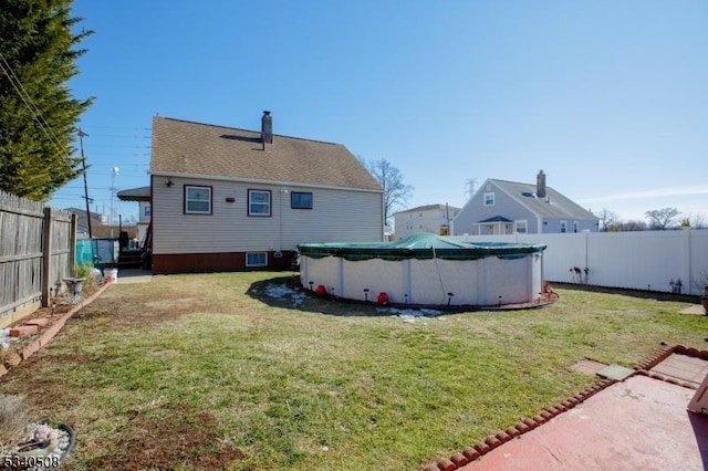 back of house with a fenced in pool, a fenced backyard, a yard, and a chimney