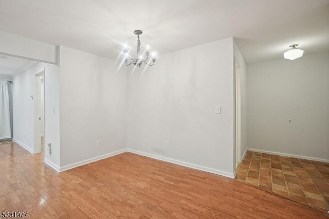 unfurnished dining area featuring light wood finished floors, baseboards, and an inviting chandelier