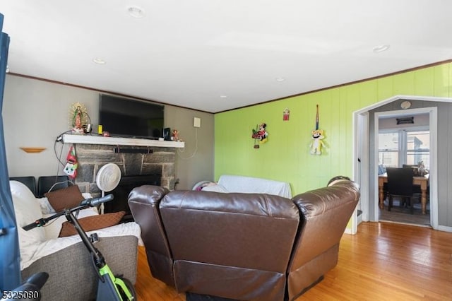 living room with crown molding, a fireplace, and light wood-style flooring