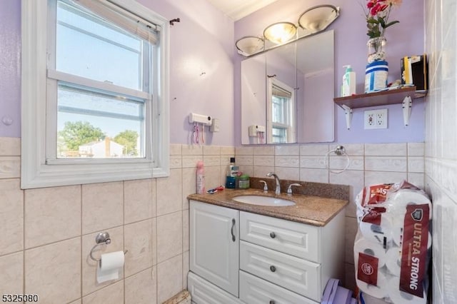 bathroom featuring a wainscoted wall, vanity, a wealth of natural light, and tile walls