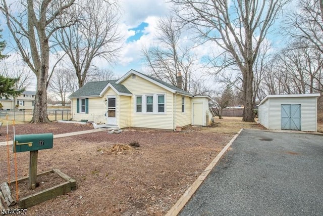 bungalow-style home featuring a storage unit, an outdoor structure, a chimney, and fence