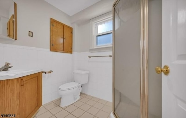 full bath featuring toilet, wainscoting, vanity, a shower stall, and tile patterned floors