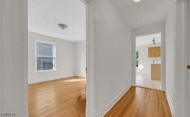 corridor with baseboards and light wood-style floors