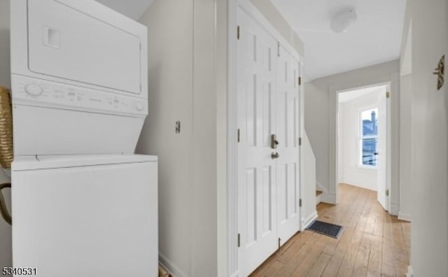 washroom featuring laundry area, light wood-type flooring, visible vents, and stacked washer / drying machine