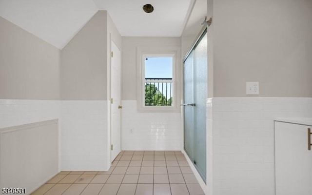 interior space with a wainscoted wall, light tile patterned floors, and tile walls