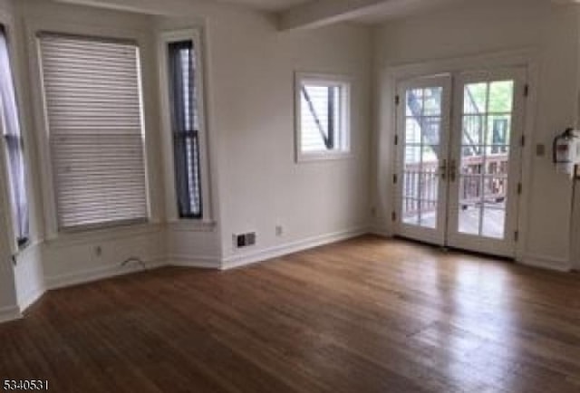 empty room featuring french doors, a healthy amount of sunlight, baseboards, and wood finished floors