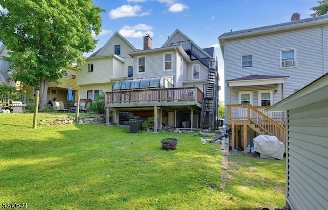 rear view of house featuring a fire pit, stairway, a deck, and a yard