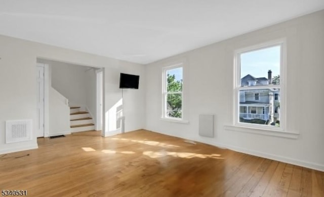 unfurnished room with visible vents, stairway, and wood finished floors