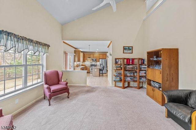 sitting room with high vaulted ceiling, light carpet, and ceiling fan