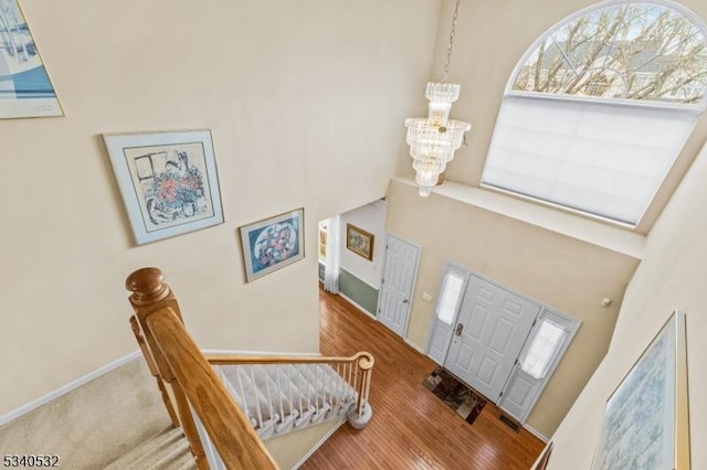 entrance foyer with an inviting chandelier, a high ceiling, baseboards, and wood finished floors