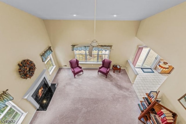 living area featuring carpet floors, a fireplace with flush hearth, high vaulted ceiling, and baseboards