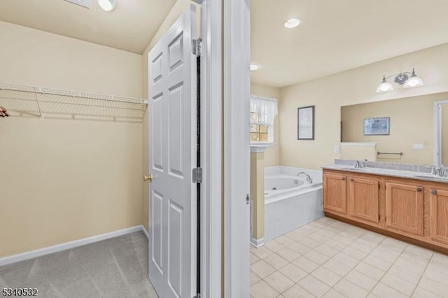 bathroom with double vanity, baseboards, a bath, tile patterned flooring, and a sink