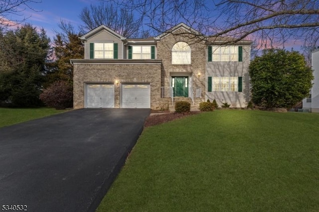 view of front facade featuring an attached garage, brick siding, aphalt driveway, and a front yard