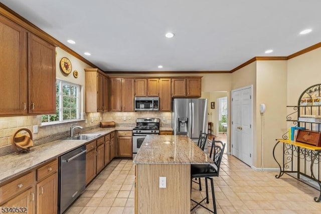 kitchen featuring a center island, a breakfast bar area, tasteful backsplash, appliances with stainless steel finishes, and a sink