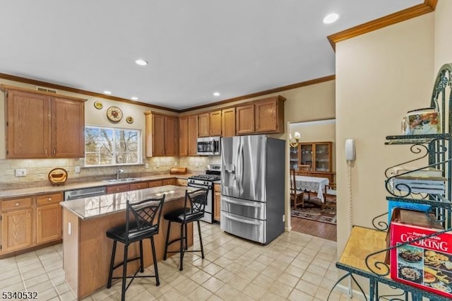 kitchen featuring stainless steel appliances, a sink, decorative backsplash, and a kitchen bar