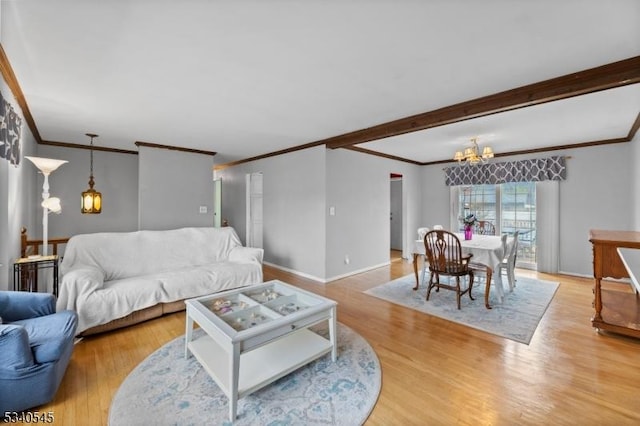 living room with light wood-style floors, baseboards, a notable chandelier, and ornamental molding