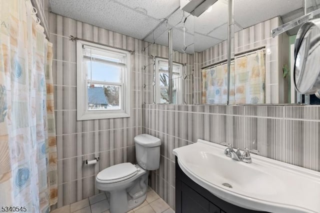 full bath featuring tile patterned flooring, toilet, vanity, tile walls, and a shower with curtain