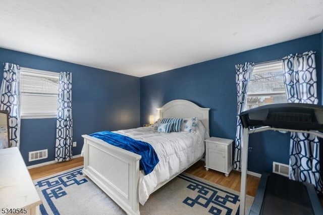 bedroom featuring multiple windows, visible vents, and wood finished floors