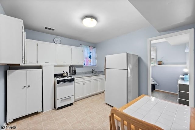 kitchen featuring light countertops, visible vents, white cabinetry, a sink, and white appliances