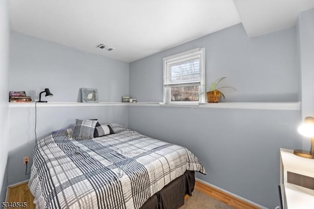 bedroom featuring wood finished floors, visible vents, and baseboards