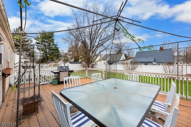 wooden terrace featuring outdoor dining space, fence, and a residential view