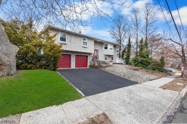 split foyer home with a front yard, stone siding, driveway, and an attached garage