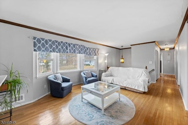 living area with light wood-type flooring, baseboards, and crown molding