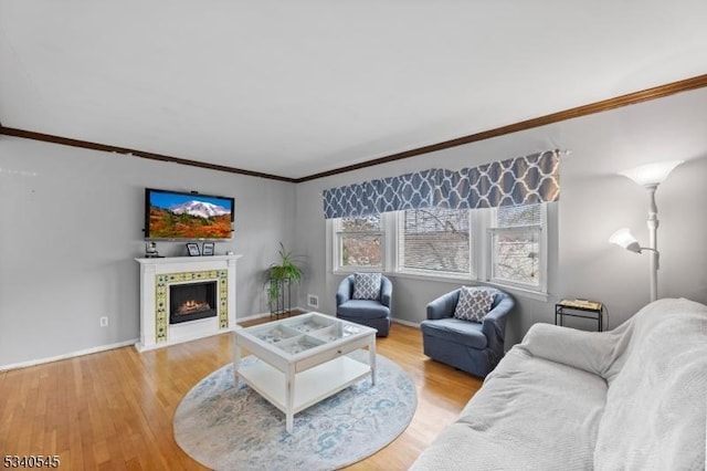 living room with a fireplace with flush hearth, ornamental molding, wood finished floors, and baseboards