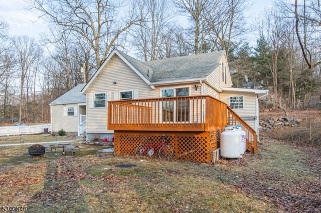 rear view of house featuring an outdoor fire pit, a deck, and roof with shingles