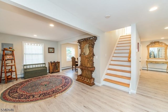 foyer featuring recessed lighting, a baseboard heating unit, wood finished floors, baseboards, and stairs