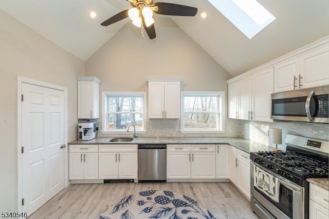 kitchen featuring stainless steel appliances, plenty of natural light, light wood-style floors, and a sink