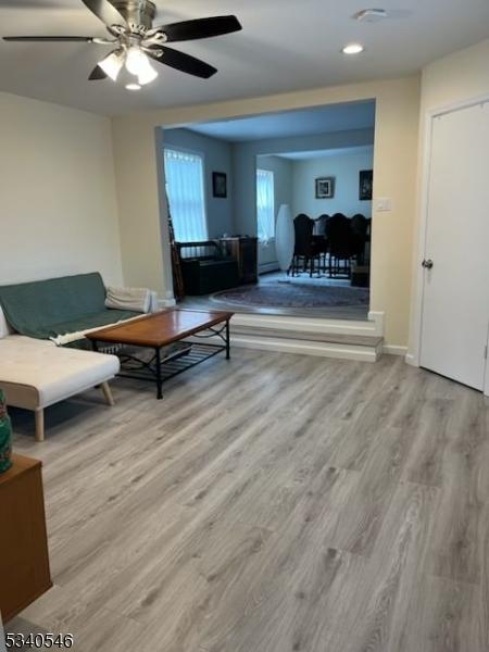 living area featuring baseboards, a ceiling fan, and wood finished floors