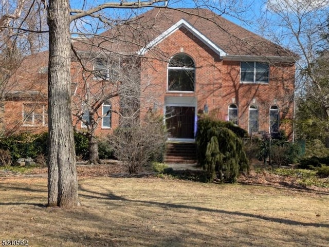 colonial house with brick siding and a front yard