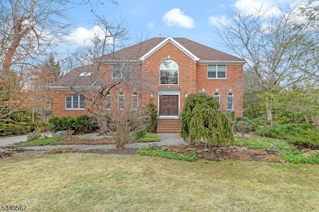 colonial inspired home with a front lawn and brick siding