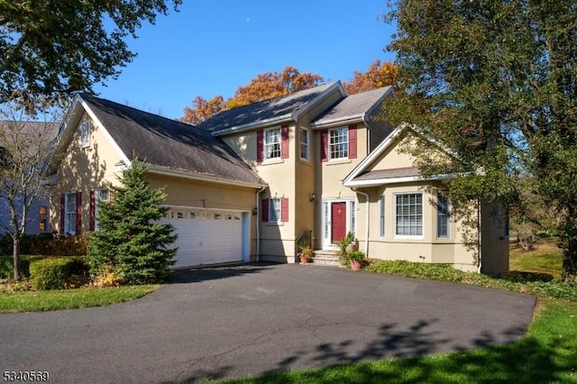 view of front of home featuring aphalt driveway, an attached garage, and stucco siding