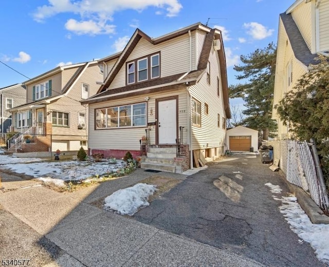 view of front of home featuring aphalt driveway, entry steps, fence, a garage, and an outdoor structure