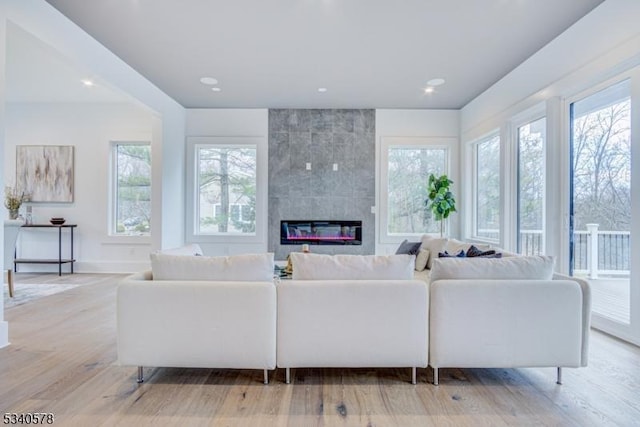 living room featuring plenty of natural light, a fireplace, light wood-style flooring, and recessed lighting