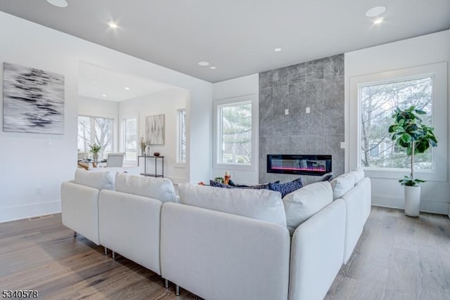 living room featuring baseboards, wood finished floors, a tile fireplace, and recessed lighting