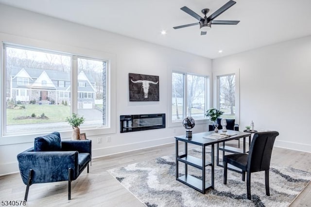 office featuring baseboards, a ceiling fan, a glass covered fireplace, light wood-style floors, and recessed lighting