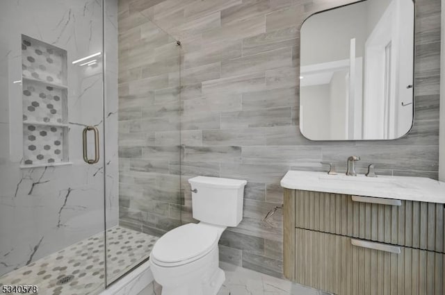 full bath featuring marble finish floor, tile walls, toilet, a shower stall, and vanity